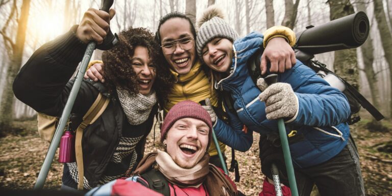 Multiracial happy friends with backpacks hiking in the forest